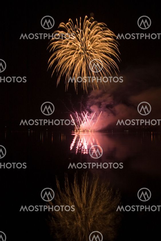 Colorful fireworks on the black sky background and water reflections