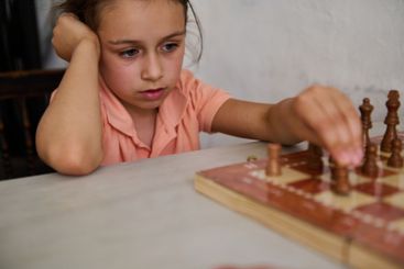 Young girl in deep concentration playing chess at home