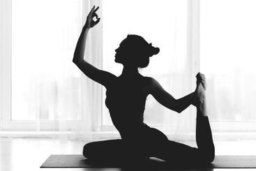 Silhouette of fit woman practicing yoga indoors over window