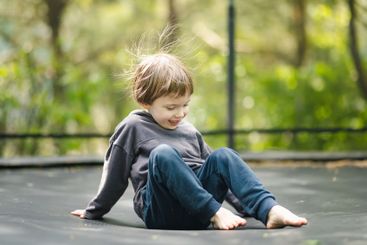 Little boy jumping on a trampoline in a backyard on warm...