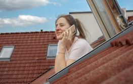 Smiling woman talking on her phone while gazing out of an...