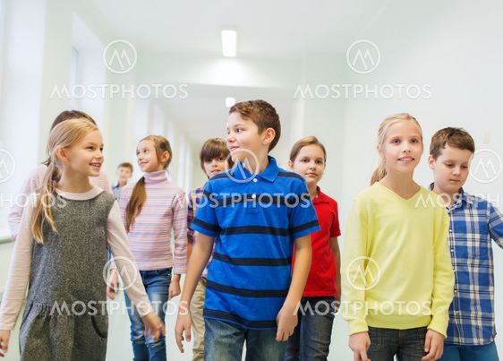 group of smiling school kids walking in corridor