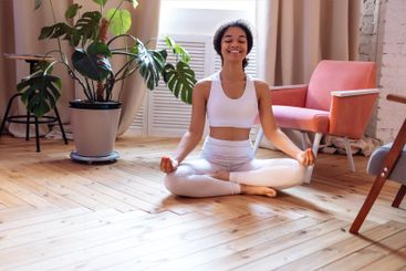 A smiling African in a white fitness suit meditates...