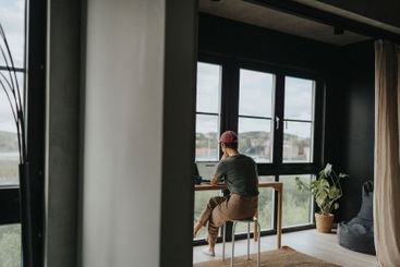 Rear view of businesswoman working on laptop while...