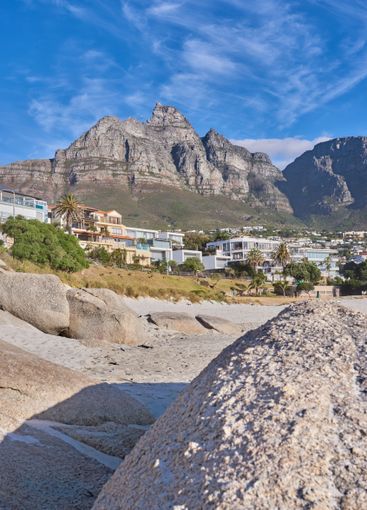 Mountain, buildings and rocks on beach with tropical...
