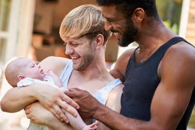 Loving Male Same Sex Couple Cuddling Baby Daughter At...