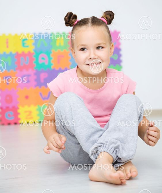 Little girl is sitting on floor in preschool