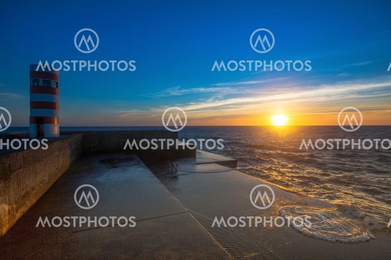 Beautiful ocean sunset at the stone pier in calm weather.