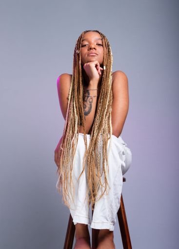 Brunette model with braids in her hair, wearing white...