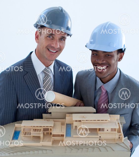 Smiling engineers with hard hats holding a model house