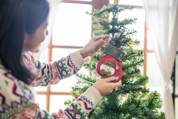 Happy asian woman Decorating Christmas tree for xmas...