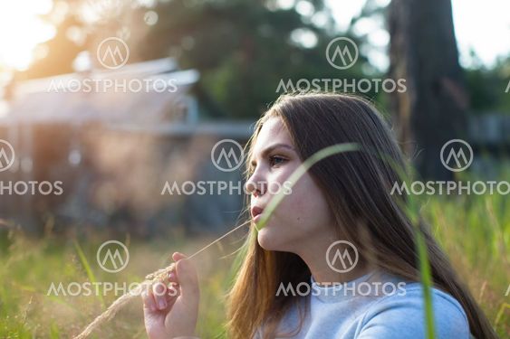 Pretty girl sitting in green grass in summer countryside.