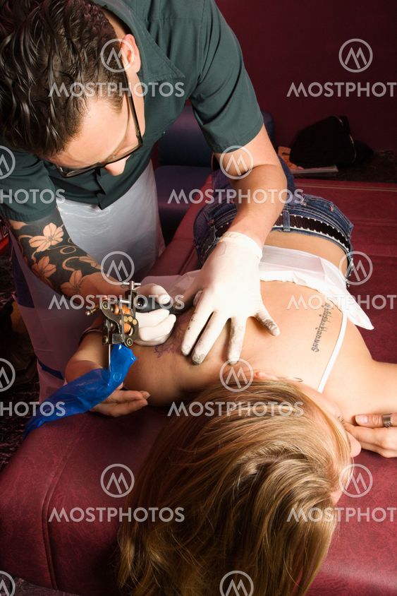 Man tattooing woman.