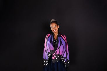 Brunette teenage girl wearing butterfly wings smiling at...