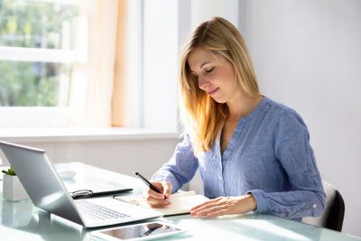 Businesswoman Writing Schedule In Diary