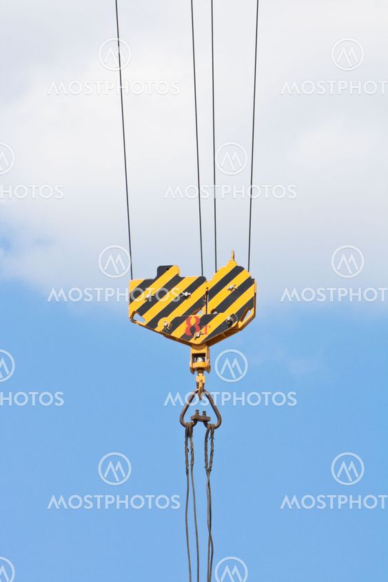 Crane hook over blue sky with clouds