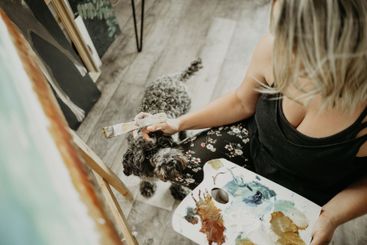 Art, painting and woman in studio with dog at home,...