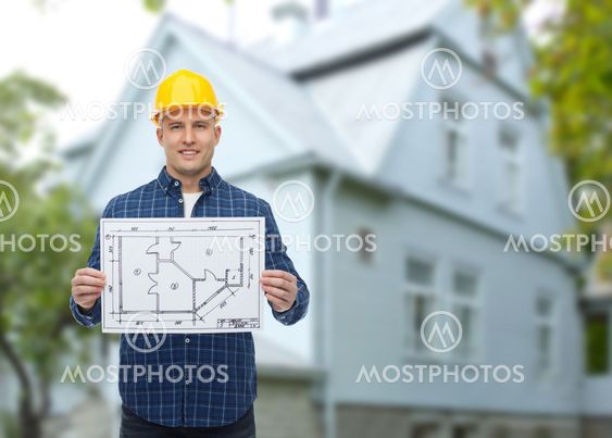 smiling builder with blueprint over house