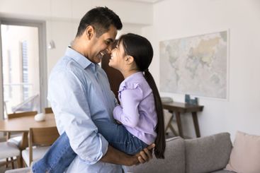 Loving Indian dad holds little cute daughter in his arms