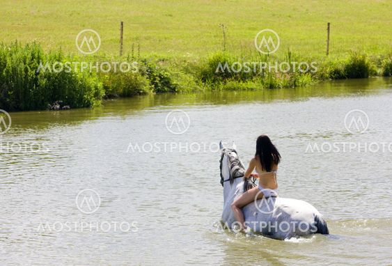 equestrian on horseback riding through water