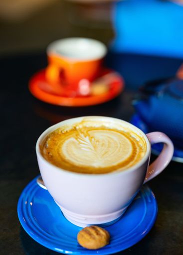 Latte with leaf art on blue saucer