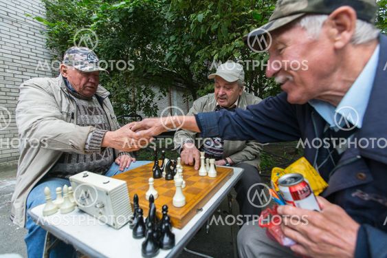 Pensioners play chess in the courtyard of an apartment...