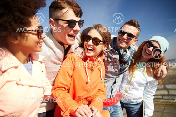 smiling friends in sunglasses laughing on street