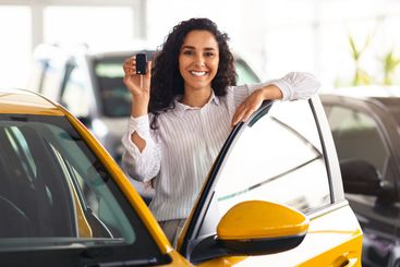 Attractive brunette woman holding key, buying new car,...