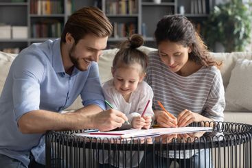 Happy parents with small daughter draw together