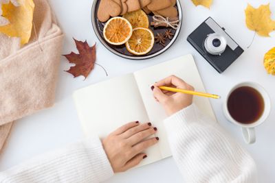woman's hands writing to notebook in autumn