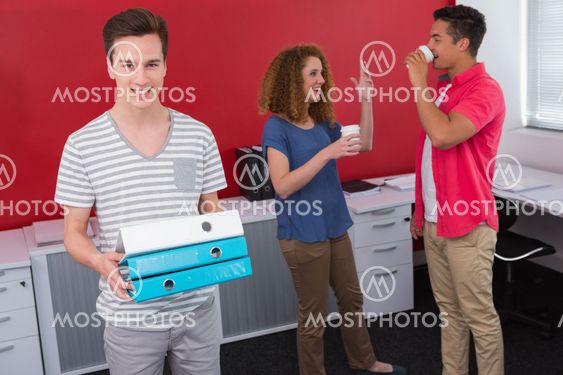 Student holding pile of ring binder near classmates with...
