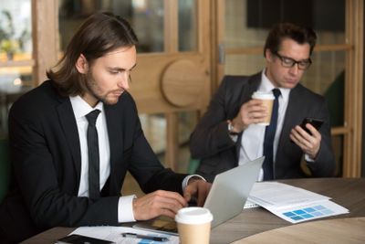 Colleagues busy using technological devices during...