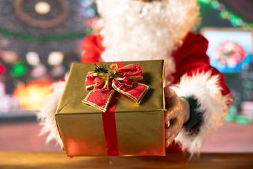 Father Christmas decorates a wrapped present box with...