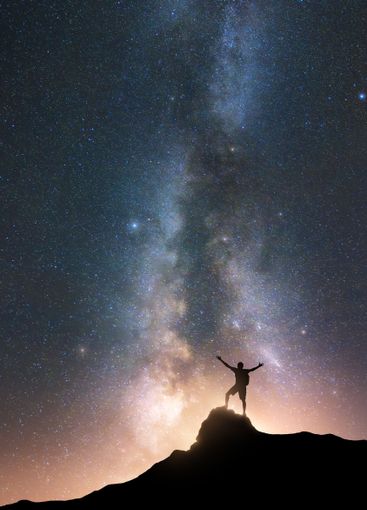 Milky Way and happy man on the mountain peak at starry...