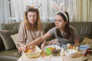 Mother And Daughter Preparing Easter Egg Decorations.