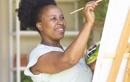 Focused happy senior african american woman holding paint pa