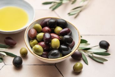 Bowl of assorted olives with olive oil and olive...