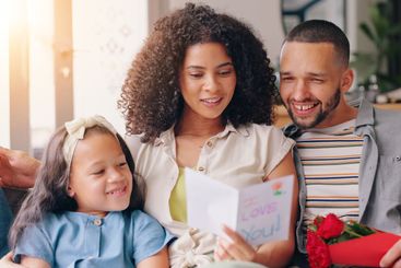 Parents, girl and flowers for mothers day in home with...