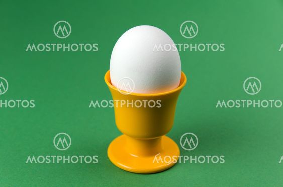 Egg in cup at green background