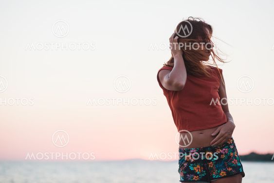Young woman enjoying sunset by the sea