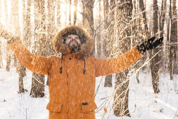Man enjoying fresh snow in winter forest. Joy, freedom,...