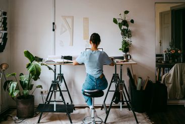 Rear view of female freelancer sitting on stool and...