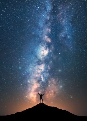 Milky Way and happy man on the mountain peak at starry...