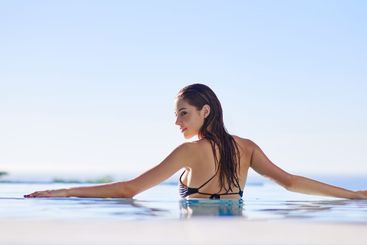 Woman, smile and back in pool with sky, relax and...