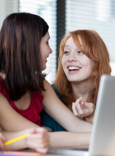 Two female college students working on a laptop computer...