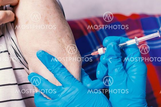 Old man ig getting coronavirus vaccine. Close-up.
