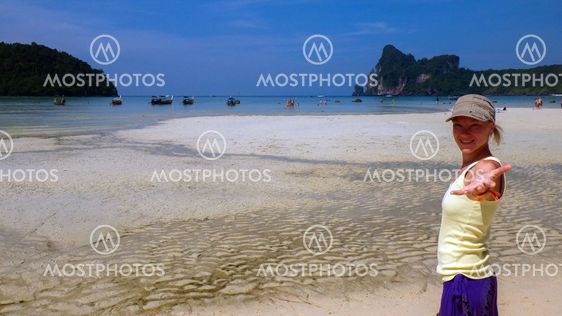 pretty girl waving by hand while standing in the sea and looking at camera