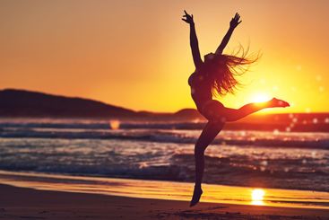Woman, sunset and jumping silhouette on seashore,...