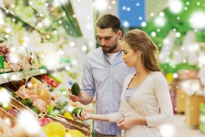 happy couple buying avocado at grocery store