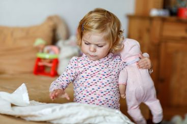 Adorable cute little toddler girl playing with doll....